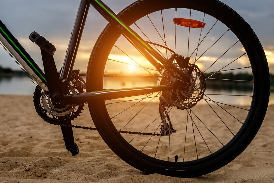 plateau et roue arrière d'une bicyclette à la plage au couché de soleil