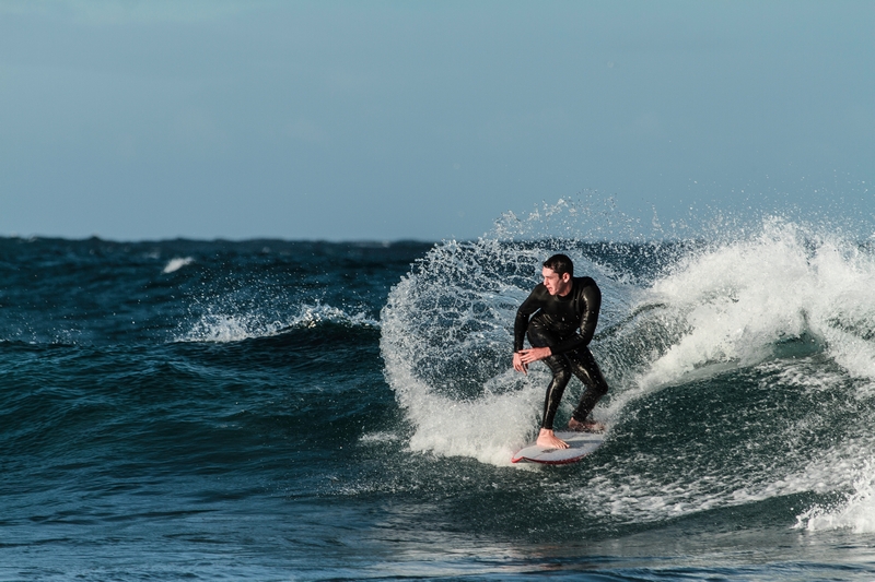 homme en combinaison qui surfe